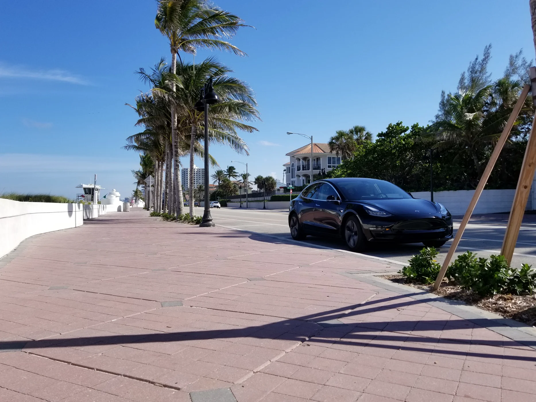 Real black Tesla Model 3 beside the coast, showing its wheels